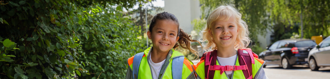 Zwei Kinder auf dem schulweg mit reflektierender Schutzweste