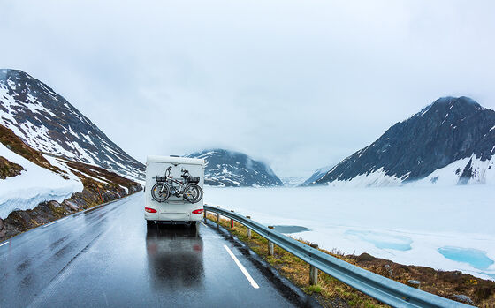 Wohnmobil fährt über eine schneebedeckte Passstrasse