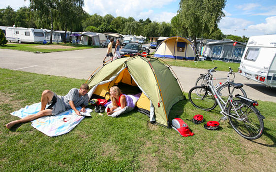 Giovane coppia che si rilassa davanti alla tenda, con le biciclette accanto