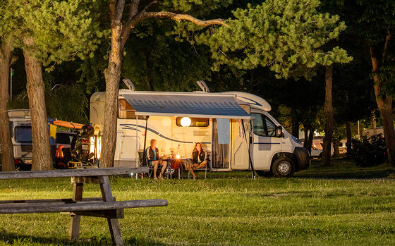 Ein paar sitzt abends gemütlich vor dem Wohnmobil