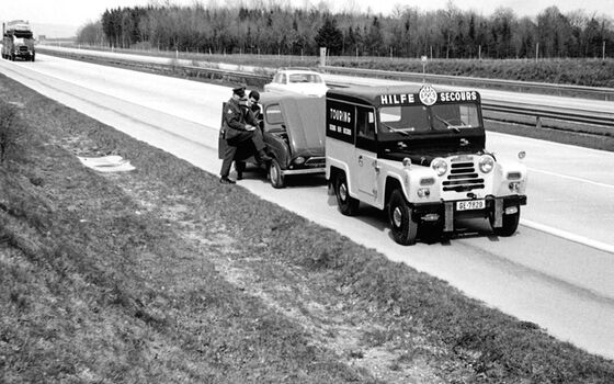 Il vecchio veicolo della pattuglia è parcheggiato accanto a un veicolo in panne sulla strada. Un pattugliatore guarda l’auto.