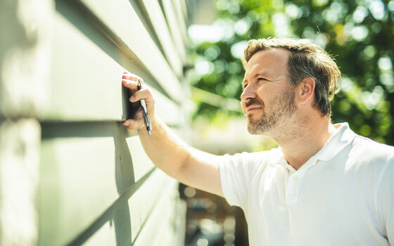 Mann inspiziert die Fassade und prüft sie auf Risse und Schäden.